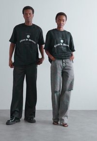Sorte grafiske t-shirts med teksten "Citizen of Denmark", parret med afslappede grå jeans med rifter og knap-front design.