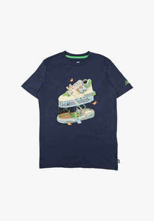 T-shirt blu navy con una grafica di una sneaker traslucida sopra una piattaforma, con accenti verdi e vari dettagli illustrati.