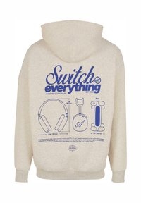 Felpa con cappuccio di un leggero beige con stampa grafica blu sulla schiena raffigurante cuffie e illustrazioni, etichetta del marchio del 2023 inclusa.