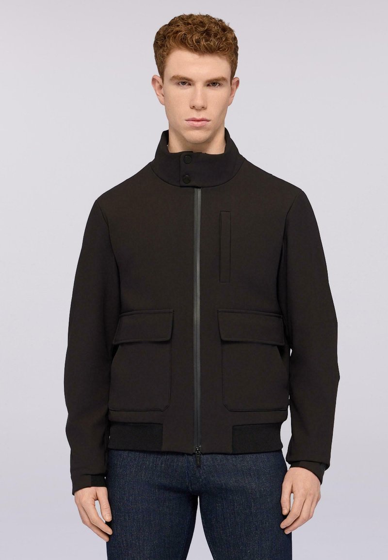 Černá bunda s vysokým límcem, předním zipem, dvěma velkými kapsami se klopami a pletenými manžetami. Vyrobena z hladkého, strukturovaného materiálu.