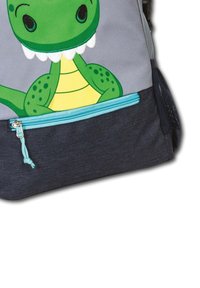 Grüner Dinosaurier-Rucksack mit einem lächelnden Gesicht, Reißverschlusstasche mit türkisfarbenen Akzenten und einem grauen Stoffkörper mit strukturiertem Finish.