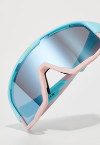 Sportsonnenbrille mit einem türkis- und pinkfarbenen Kunststoffrahmen, der ein Wickeldesign aufweist und mit spiegelnden blauen Gläsern ausgestattet ist. Verstellbare Nasenbrücke inklusive.
