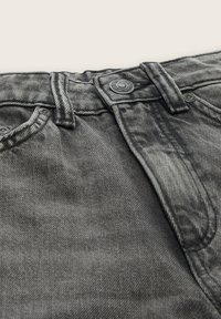 Nærbillede af grå denimjeans talje med bæltestropper, metal knap og synlige søm detaljer.
