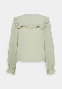 Light green top featuring long sleeves, a textured fabric with a grid pattern, and ruffled accents along the neckline and cuffs.