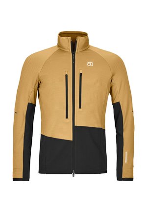 Hellbraune und schwarze Jacke mit durchgehendem Reißverschluss und Stehkragen, zwei vertikalen Reißverschlusstaschen auf der Brust sowie schwarzen Einsätzen vorne unten und an den Ärmeln.