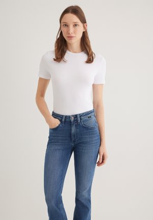 White short-sleeve fitted t-shirt made of soft cotton, paired with high-waisted blue denim flared jeans featuring subtle fading.