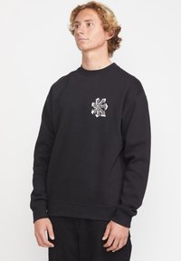Sudadera negra hecha de una mezcla de algodón, con un cuello redondo, puños y dobladillo acanalados, y un diseño gráfico texturizado en el pecho.