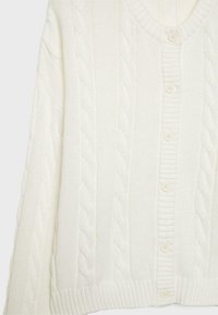 Hvid strikket cardigan med v-hals, kabelmønster, ribbet kant og seks runde knapper foran. Blød tekstur.