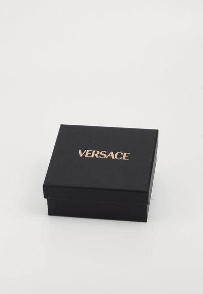Crni pravokutni poklon kutija s glatkom teksturom i poklopcem s šarkom, s zlatnim "VERSACE" logotipom na gornjoj površini.