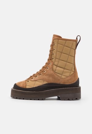 Brauner hoher Schnürstiefel mit gesteppte Stoffeinsätzen, Wildlederakzenten, dicker Laufsohle mit Profil und Zuglasche an der Rückseite.