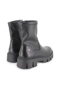 Botas de tobillo de cuero negro con suela de goma gruesa, que presentan una textura suave, cierre de cremallera y un pequeño logo en el costado.