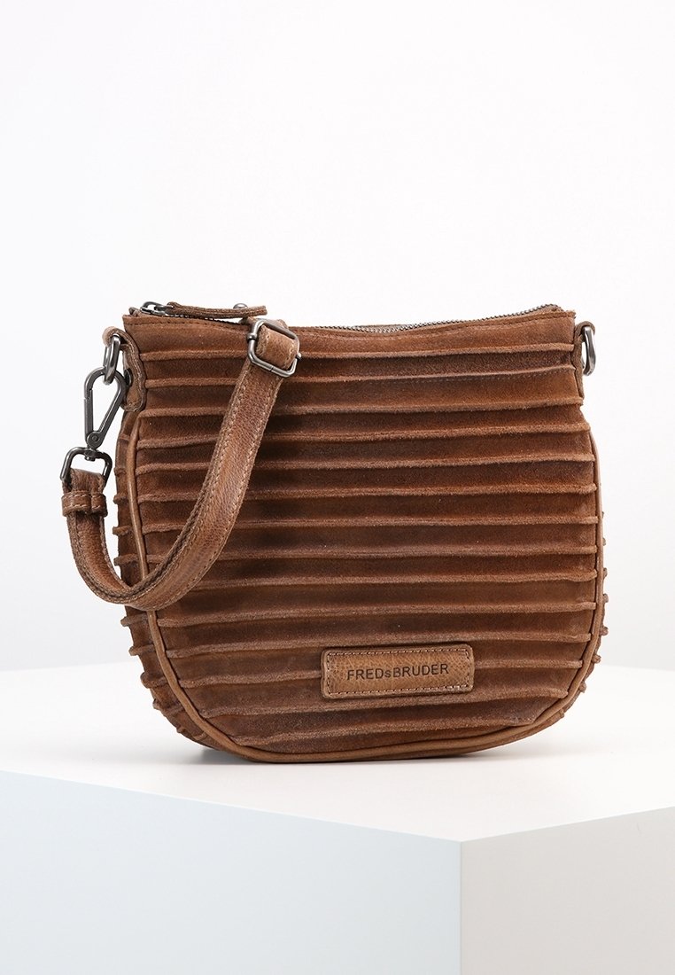 Brązowa zamszowa torba na ramię z ryflowaną fakturą, zamknięciem na zamek błyskawiczny, regulowanym paskiem oraz prostokątną łatką z logo. Kompaktowy i zaokrąglony kształt.