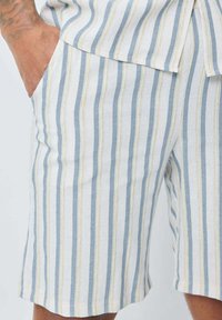 Shorts rayés en bleu clair et crème avec une texture semblable à du lin, dotés de poches latérales et d'une coupe décontractée.
