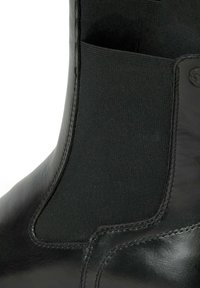 Bottine en cuir noir avec panneau latéral élastique et coutures détaillées sur la partie supérieure de la chaussure.