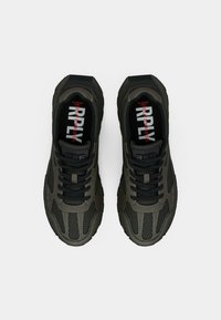 Dark green athletic shoes with a textured upper, black laces, and a cushioned sole. Features visible branding on the insoles.