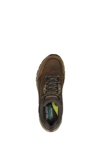 Zapatilla de cuero marrón con detalles de malla, punta redonda, cordones y suela de goma. Presenta una plantilla acolchada y un forro interior en contraste.