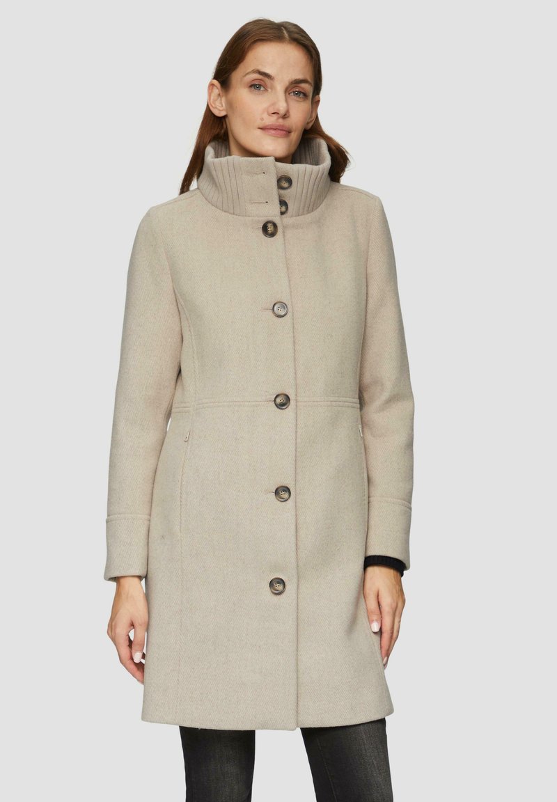 Beige wolmix jas met een hoge nek, voorzien van vijf knopen aan de voorkant, zijzakken en een geribbelde kraag. Soepele textuur en getailleerde pasvorm.