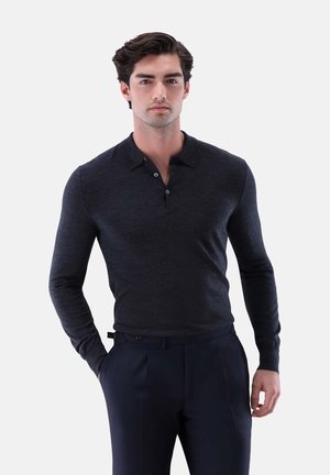 Dunkelgraues langärmeliges Polohemd aus weichem Material, mit Kragen und einer Knopfleiste mit drei Knöpfen, kombiniert mit maßgeschneiderten navyblauen Hosen.