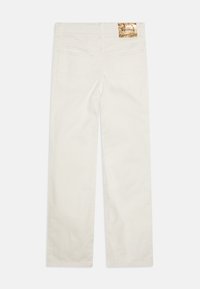 Valged denim püksid, sirge jalaga disain, viie taskuga ja kullafoiliga logoetikett vööl. Sile tekstuur.