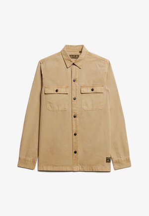 Lichtbruine button-up shirt met twee voorzakken, zwarte knopen en gestikte details. Tijdloze pasvorm met kraag en zijlabel.