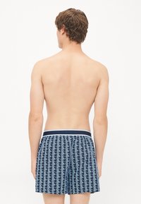 Șorturi de baie bleumarin cu un model geometric alb, talie elastică cu bandă contrastantă, lungime până la mijlocul coapsei, material ușor.