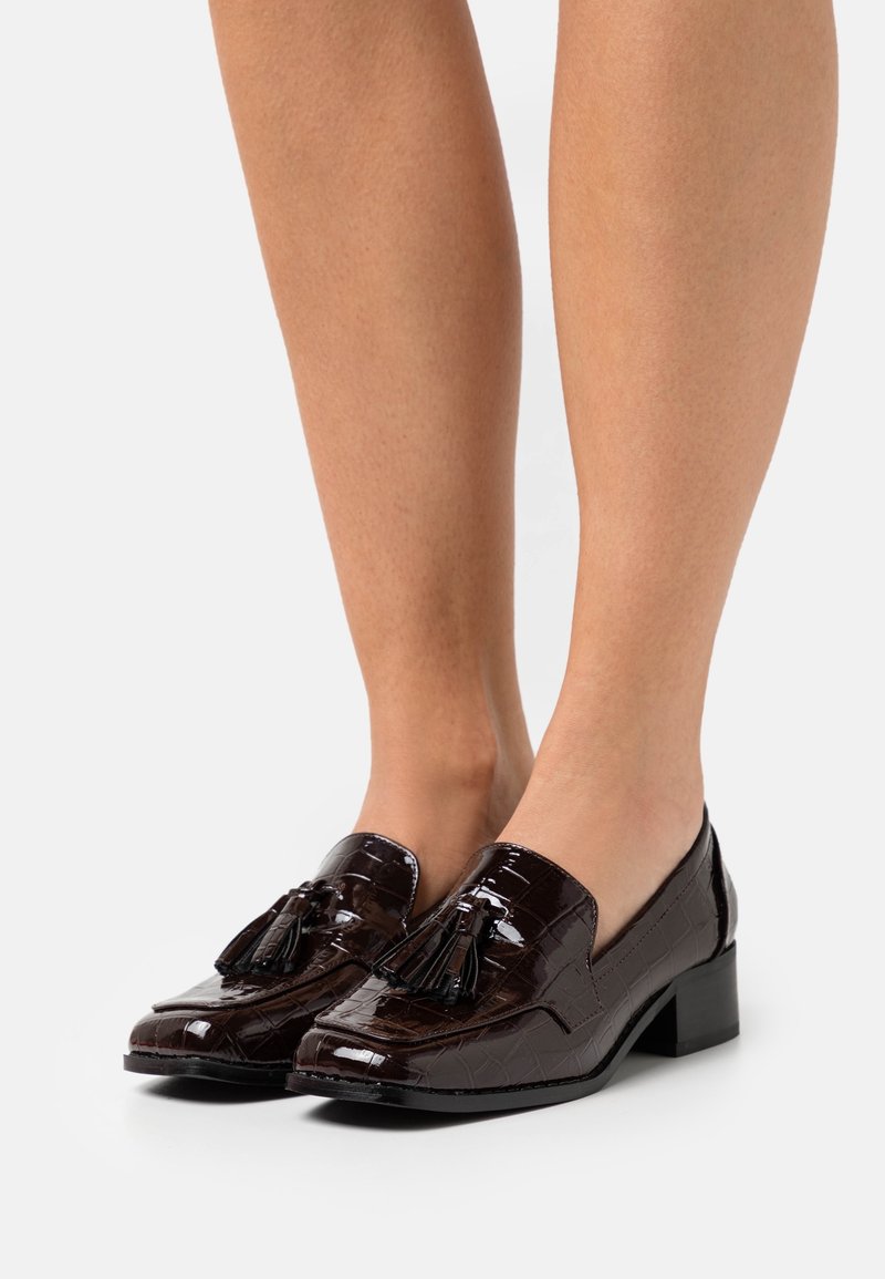 Mocassins en cuir verni marron avec un motif crocodile et des accents de pampilles surélevés ; talon bas bloc et bout arrondi.