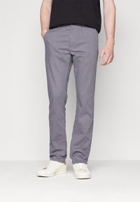 Šedé textilní kalhoty s jemným vzorem, úzký střih, přední kapsy a plochý přední díl, spárované s bílými teniskami.