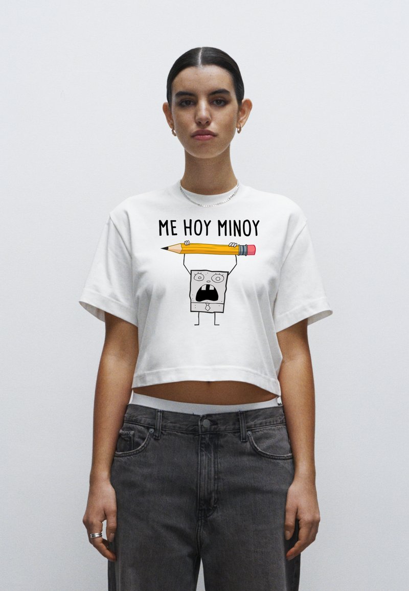 Bílý zkrácený tričko s potiskem pohádkové postavy, která drží žlutou tužku, a černým textem "ME HOY MINOY" nad grafikou.