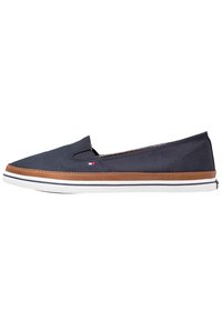 Navy slip-on casual shoe with brown trim, white sole, small red and white logo on side, and elastic gusset for easy wear.