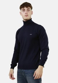Maglione a collo alto blu navy con design aderente, realizzato in un tessuto morbido. Presenta un piccolo logo sul petto e polsini e orlo a coste.