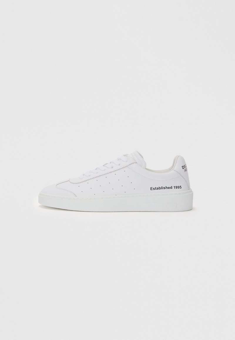White sneaker with perforated design, flat sole, and rounded toe. Features lace-up closure and "Established 1995" text on the side.
