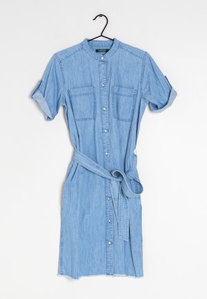 Lichtblauwe denim jurk met knopen, korte opgerolde mouwen, borstzakken en een ceintuur, hangend aan een zwarte hanger.