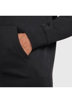 Hand in de voorzak van een zwarte hoodie, met zicht op de mouwboord en de stoftextuur tegen een effen achtergrond.