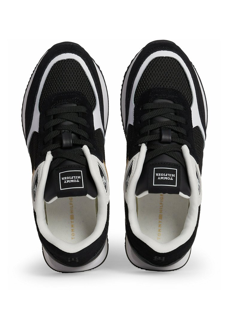 Zapatillas deportivas en blanco y negro con materiales de malla y gamuza, que cuentan con una suela acolchada, puntera redondeada y cordones a través del empeine.
