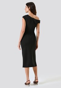 Schwarzes, tailliertes Kleid mit schulterfreiem Design, knielangem Saum und einem Reißverschluss auf der Rückseite. Glatter Stoff und minimalistischer Stil.