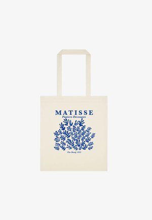 Beżowa torba typu tote z niebieskim abstrakcyjnym wzorem liści i tekstem "MATISSE Papiers Découpés The Sheaf, 1953" na przedzie.