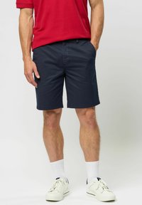 Navy shorts made of cotton blend, featuring a relaxed fit, side pockets, and a clean hem, paired with white sneakers and socks.