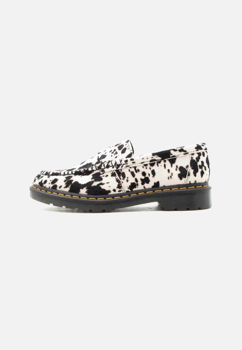 Mocassin slip-on blanc et noir à pois, avec une semelle épaisse noire et une couture jaune le long du bord de la semelle, vue de côté sur fond uni.