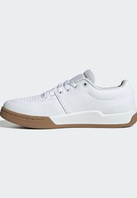 Sneaker bianco con superficie testurizzata, pannello laterale liscia e suola in gomma marrone. Dotato di lacci rotondi e perforazioni per la traspirabilità.