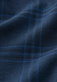 Tissu bleu marine avec un motif à carreaux subtil comportant des lignes bleues. La texture semble lisse avec un léger éclat, indiquant un tissage doux.