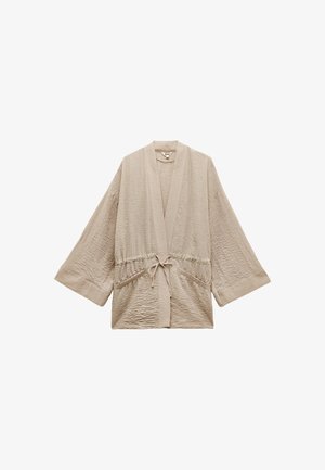 Bata de estilo kimono en beige, ligera, con mangas anchas, cintura fruncida y lazo frontal. Tela texturizada con pliegues sutiles, que cuenta con bolsillos laterales.