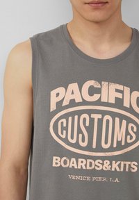 Szary bezrękawnik z dużą, wyblakłą różową grafiką z napisem "PACIFIC CUSTOMS BOARDS&KITS VENICE PIER, L.A."