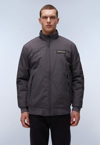Grå zip-up bomberjakke med høj krave, zip-lukkede sidelommer, elastiske manchetter og kant, prydet med et logo på brystet.