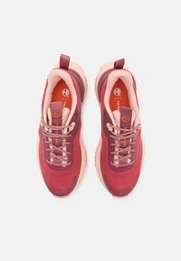 Paire de chaussures de sport rouges et roses avec lacets, semelles rembourrées et semelles intérieures de marque, vues du dessus sur un fond blanc.