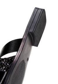 Infradito in plastica nera con un design a tracolla intrecciata, suola piatta con scanalature orizzontali e tacco testurizzato per una presa migliore.