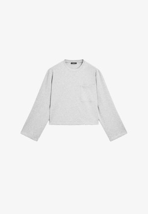 Chemise grise à manches longues raccourcie en tissu doux. Elle présente un col rond et une poche poitrine. Texture lisse avec un design décontracté.