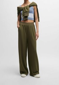 Svetle modré a bílé pruhované crop top, olivově zelené široké kalhoty s elastickým pasem, se bočními kapsami a bílé tenisky.