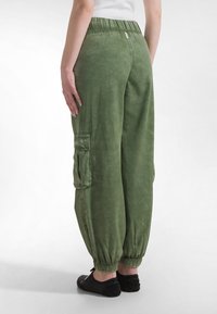 Grønne cargobukser med afslappet pasform, elastisk talje og elastiske manchetter. Har sidelommer og en blød tekstur.