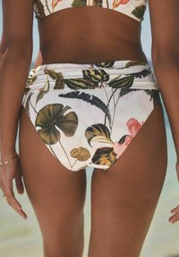Aukšto liemens bikini kelnaitės, dekoruotos gėlių raštu su žaliais lapais ir rožinėmis gėlėmis ant balto fono. Sklandi medžiagos tekstūra.