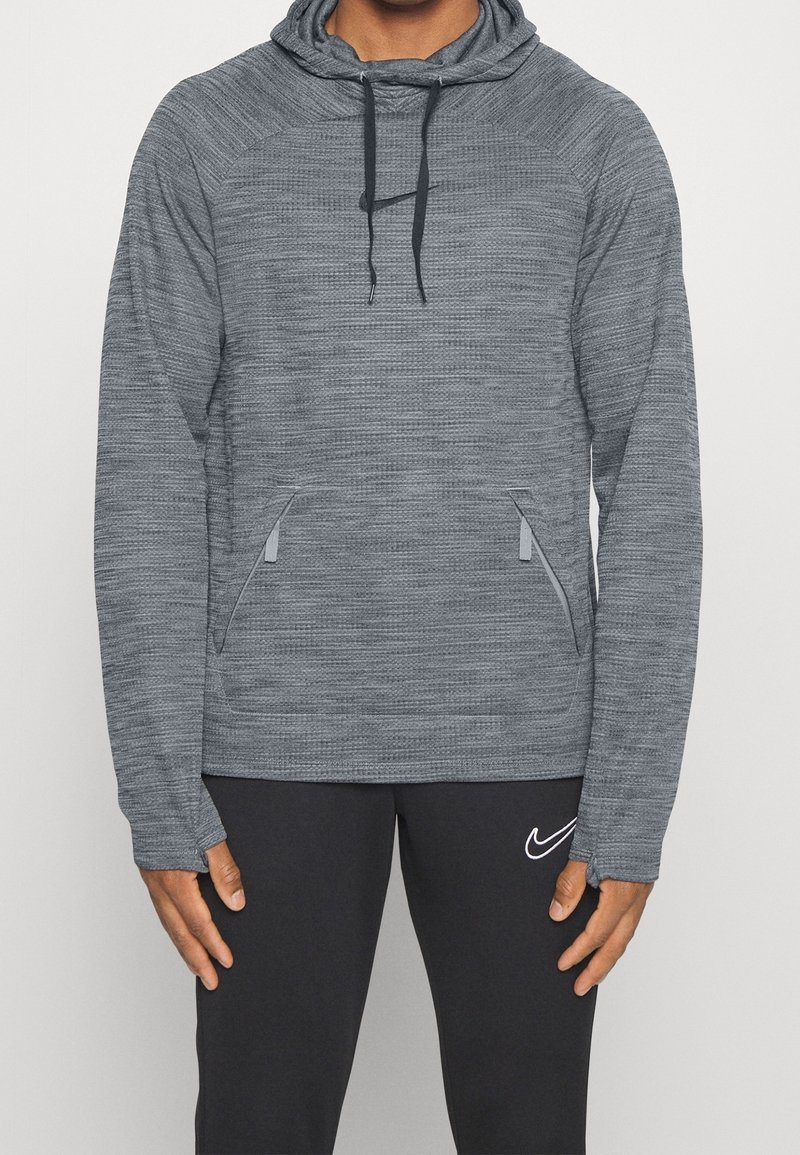 Szary sportowy hoodie z teksturowanej tkaniny, z kapturem na sznurki i bocznymi kieszeniami. Czarne akcenty zawierają logo z przodu.